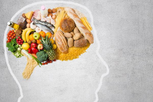 Stock photo showing a head outlined, with photos of various foods arranged in the brain area, to reflect how diet affects the mind.